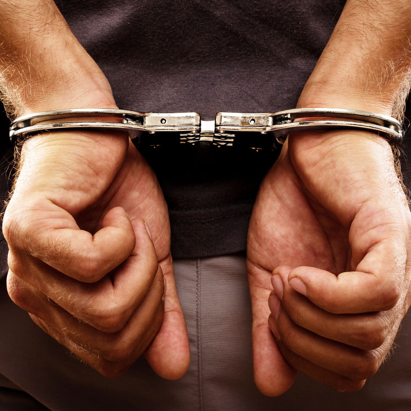 Close-up of handcuffs on a man’s wrists