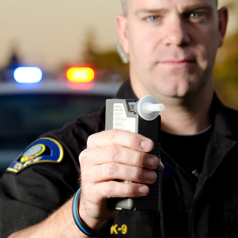 Close-up of a police officer holding a Breathalyzer