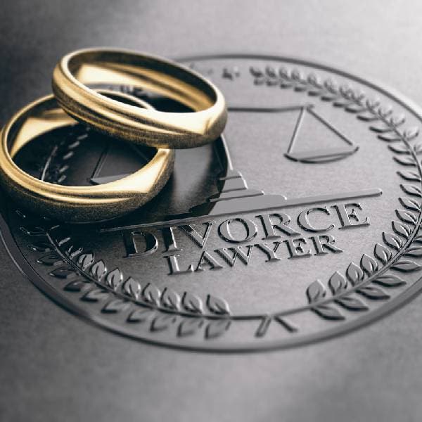 Close-up of two gold wedding rings on top of an embossed divorce lawyer sign