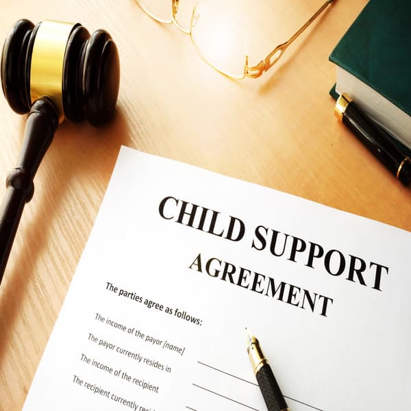 A close-up of a paper that says child support agreement with a gavel and black pen
