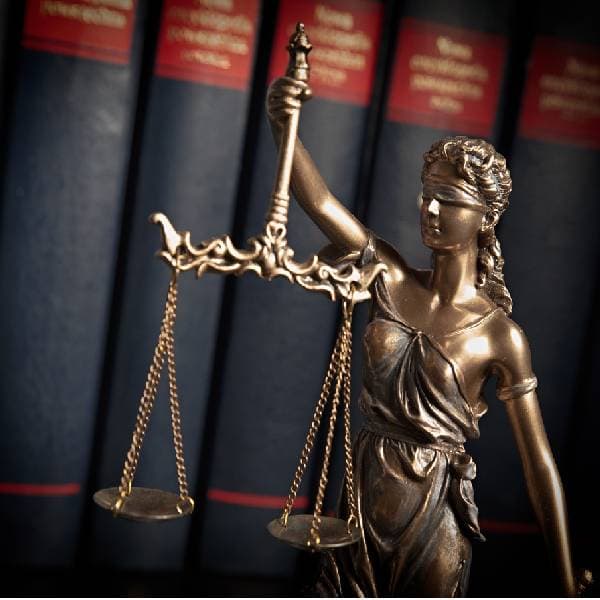 Bronze statue of Lady Justice with law books in the background