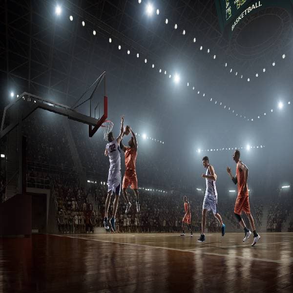 Basketball player in orange tries to score with player in white uniform defending